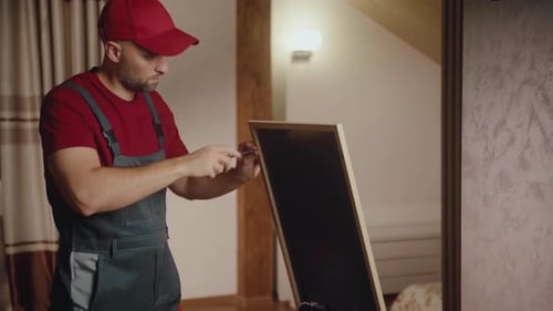 Repairman Works on Fixing a Broken Mirror in a Cozy Interior Setting During Daytime