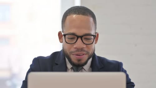 Close Up of African Businessman Chatting Online on Laptop