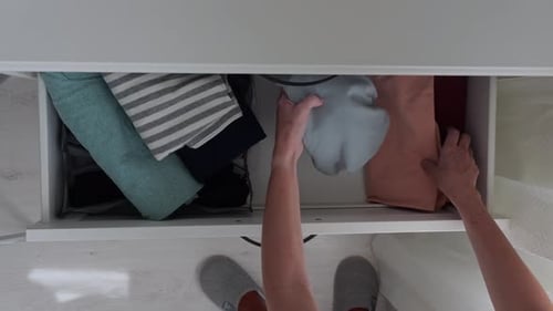 Woman Packing Clothes Into Drawer