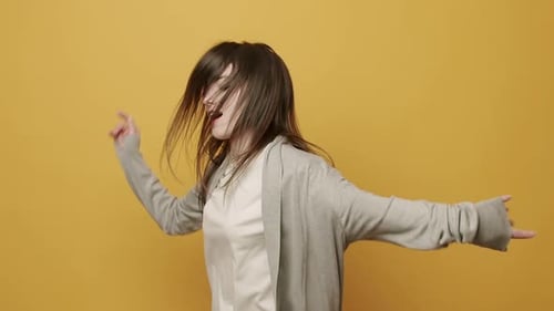 Woman Dancing Energetically Against a Yellow Background