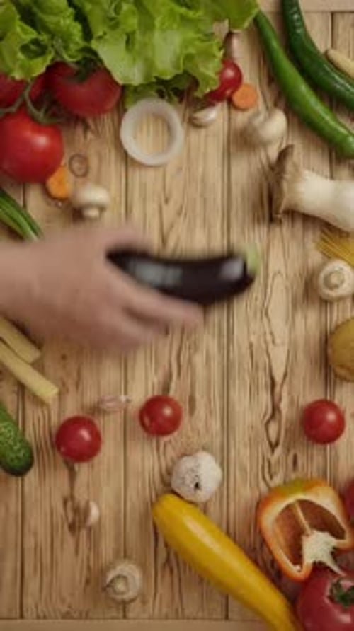 Vertical of Faceless Cook Taking Eggplant From Wooden Table