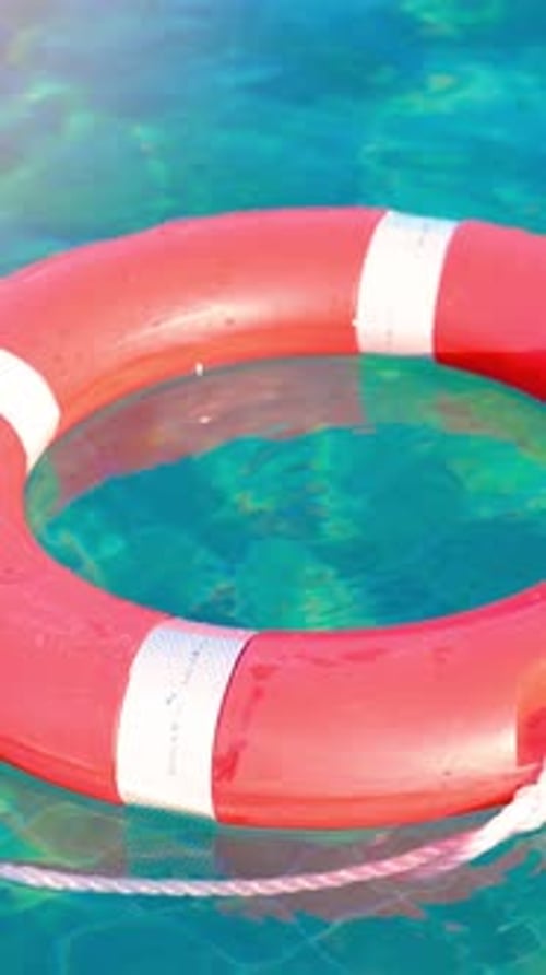 Une bouée de sauvetage rouge vif flotte gracieusement dans les eaux turquoises sereines d'une plage paradisiaque