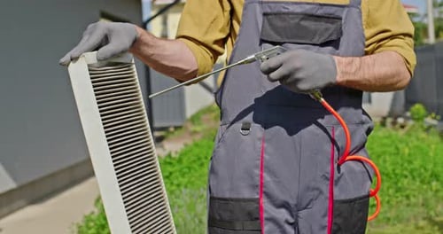 Trabajador limpiando un filtro de aire sucio con aire comprimido