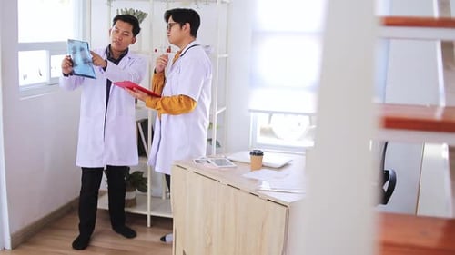 Doctors in white coats analyze X-ray results discussing patient care in modern medical office