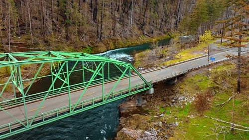 Red car crossing the little bridge above the narrow mountainous river.