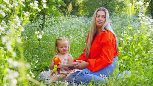 A Woman is Looking at the Camera and Enjoying the Nature Around and Waving a Fan