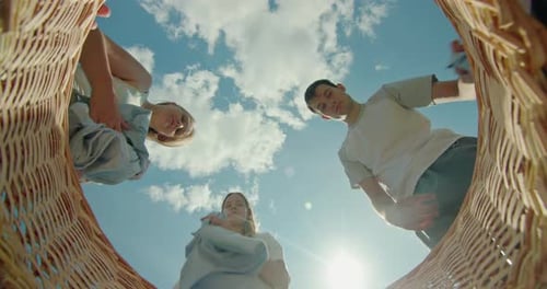 Family Tossing Bed Linens Into a Laundry Basket with a View From Inside the Basket Against a