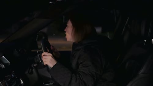 Angry female driver stuck in traffic jam at night. The girl is frustrated and shouting and honking h