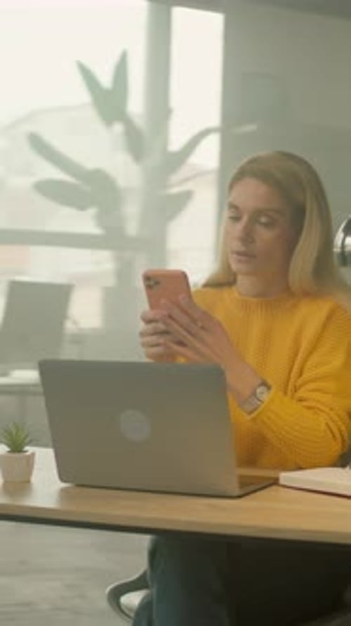 Woman Typing on Laptop and Checking Smartphone