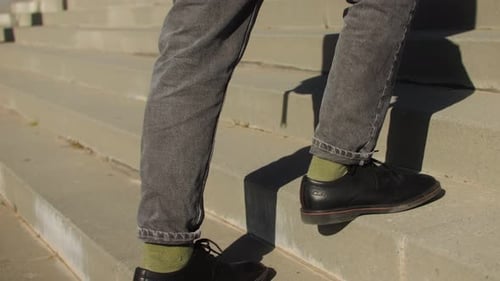 A Man Climbs the Stairs in the City Holding the Handrail Against the Wind