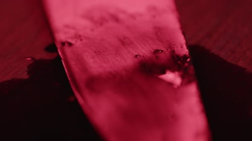 Extreme close up of a blood covered knife in a puddle of blood