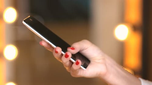 Woman uses mobile device indoors with blurred lighting