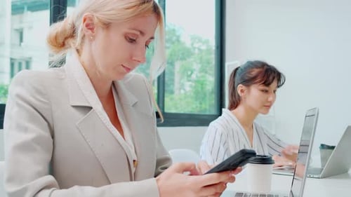 Young caucasian businesswoman using laptop computer and smart phone working at the office.