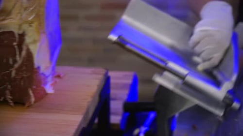 Gloved Hand Slicing Meat with a Professional Slicer