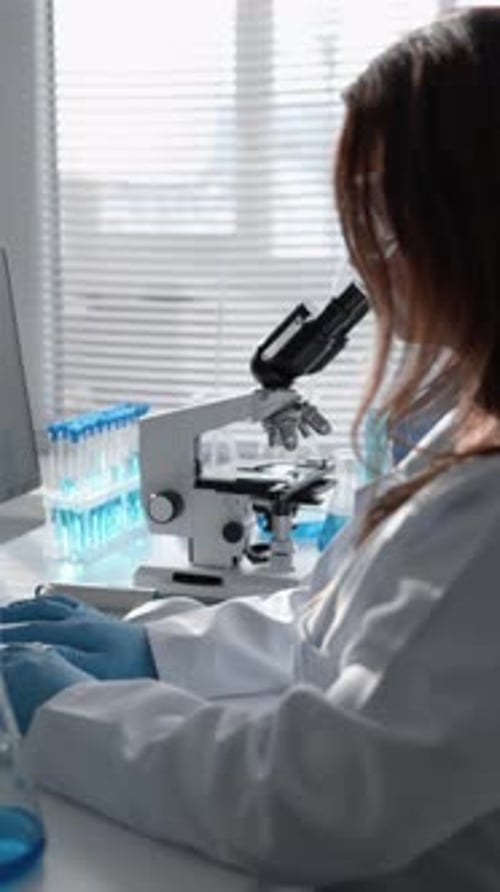 Scientist Analyzing Data in Modern Laboratory with Microscopes and Test Tubes