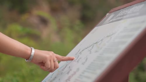 Woman Points at Information Sign on Coastal Trail