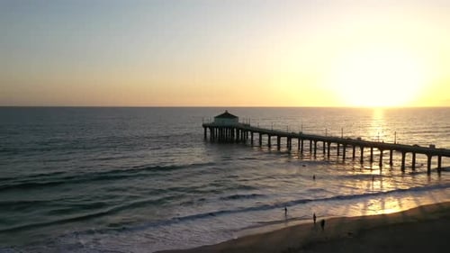People standing on the Sandy Beach Watching the Silhouette of the Pier at Sunset in Manhattan Beach