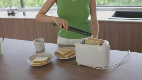 Woman Using Tongs to Remove Toast