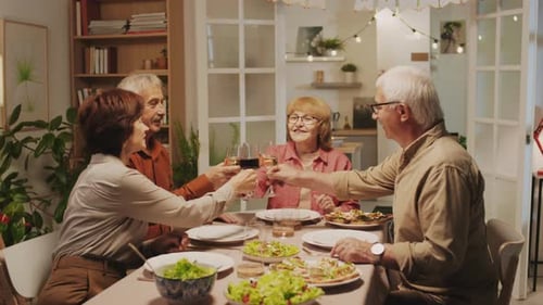 Four Friends Toasting Around Dinner Table in Home