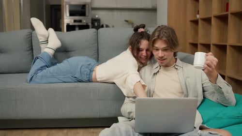 Young Couple Relaxing At Home With Laptop Computer