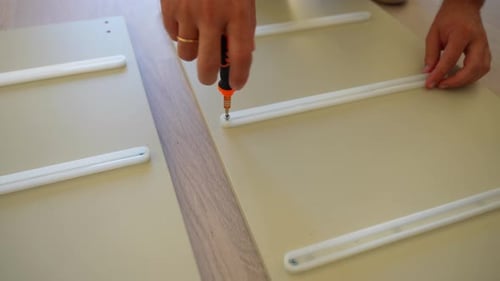 Close-up of male hand assembling furniture screwing plastics in a wood plank