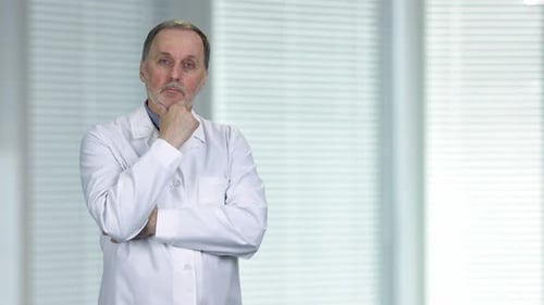 Thoughtful Doctor in White Coat Standing in Workplace