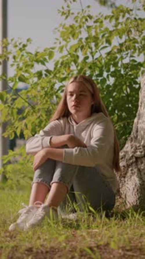 Woman Sitting Under Tree on a Sunny Day