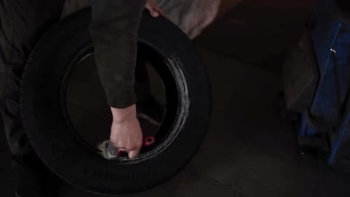 Mechanic Applies Liquid to Inside of Black Tire