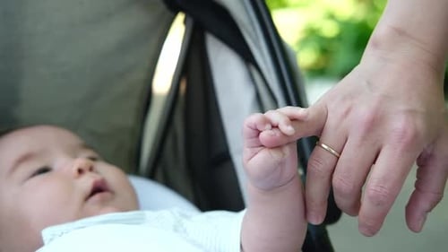 Infant Grasping Adult's Finger in Stroller