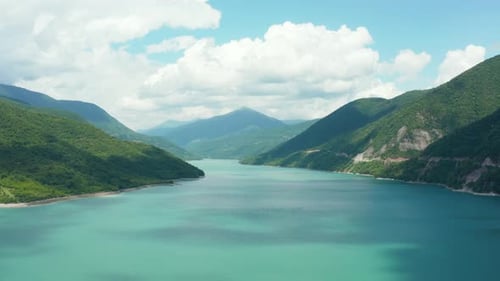 Stunning aerial establishing shot of mountain valley turquoise lake surrounded by lush forest. Mount
