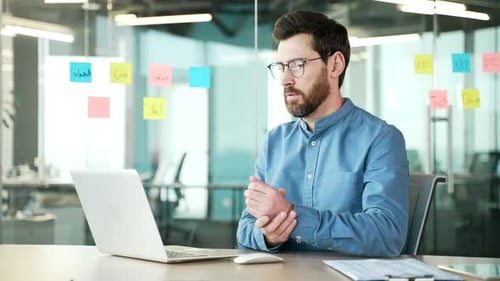Man at Computer Rubs Aching Wrist in Office