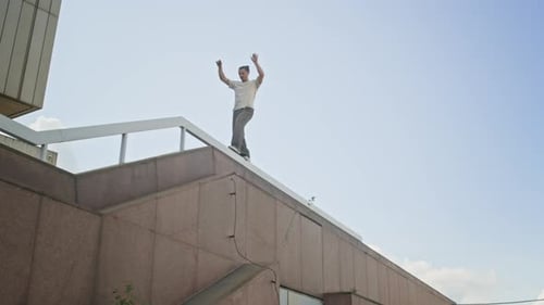 Acrobatic Young Parkour Artist Practicing Balance while Climbing Down Building