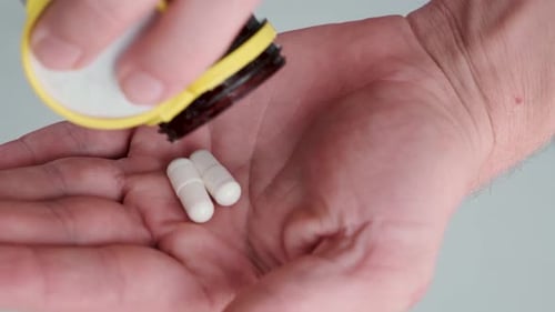 Hand Holding White Pills for Health Purposes
