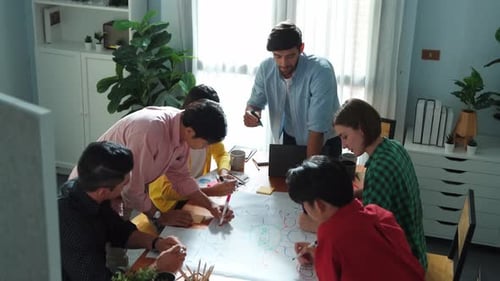 Creative Team Brainstorming and Writing on Large Poster