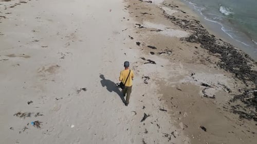 Aerial View of Man Walking with Metal Detector Along Sandy Beach Near Sea Searching for Treasure on
