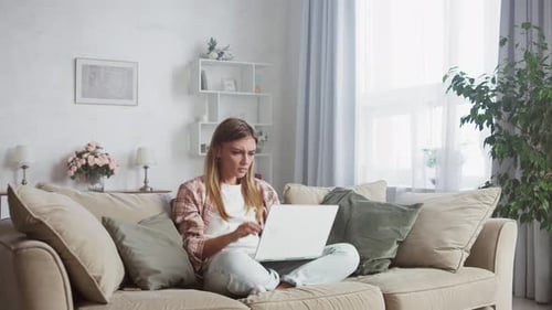 Woman Frustrated Working on Laptop on Couch
