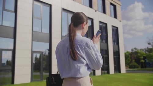 Businesswoman Walks Near Business Center and Talking with Colleague on Phone