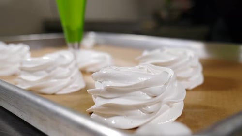 Konditor, der Pavlova-Kuchen herstellt, drückt Baiser aus der Gebäckhülle und spritzt Baiser beim Backen