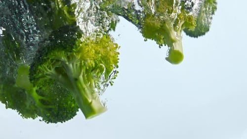 Clusters Fresh Broccoli Floating in Transparent Water with Bubbles Closeup. Green Ripe