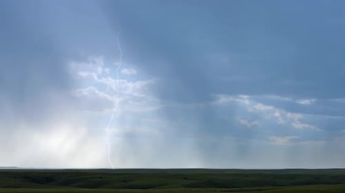 Blitze durchziehen Regenbänder unter einer sommerlichen Gewitterwolke