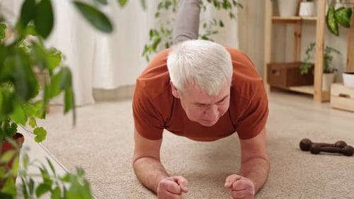 Glücklicher lächelnder reifer älterer Mann, der zu Hause Gymnastikübungen macht Konzept eines gesunden Lebensstils