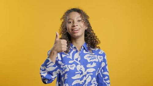 Happy Woman Gives Thumbs Up on Yellow Background