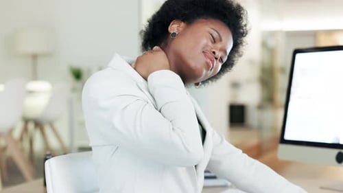Woman suffering with neck pain from long working hours at desk in an office