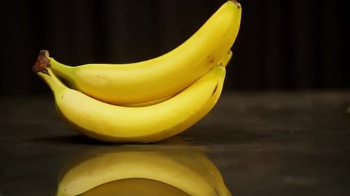 A Branch of Ripe Yellow Bananas Sways on the Table