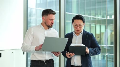 Businessmen Collaborating in a Modern Office Reviewing Documents and Discussing Project Strategies