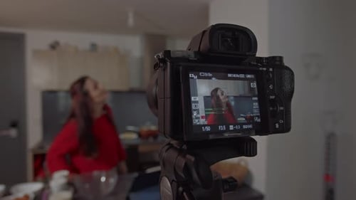 Mujer joven bailando y grabando un tutorial de cocina en el apartamento