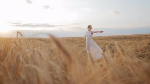 Attractive Female Wearing White Dress Dancing Amidst Field