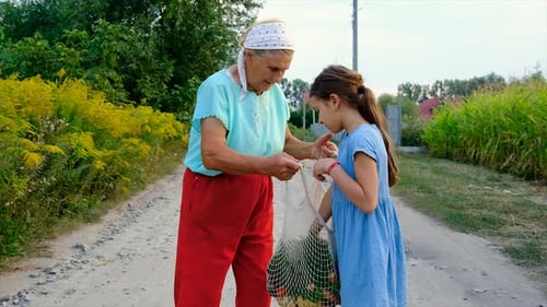 Grandmother Gives Apple to Child on Dirt Road
