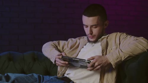 Young Adult Relaxing at Home Playing Video Game