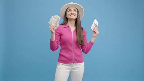 Cheerful Woman Holding Money and Tickets on Blue Background